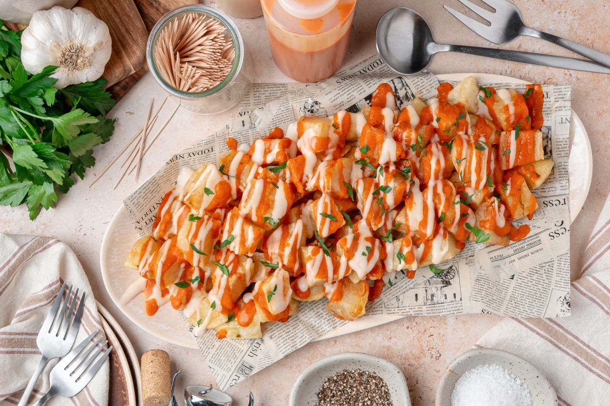 Patatas Bravas Platter Platter of patatas bravas topped with homemade bravas sauce, garlic aioli, and fresh parsley.