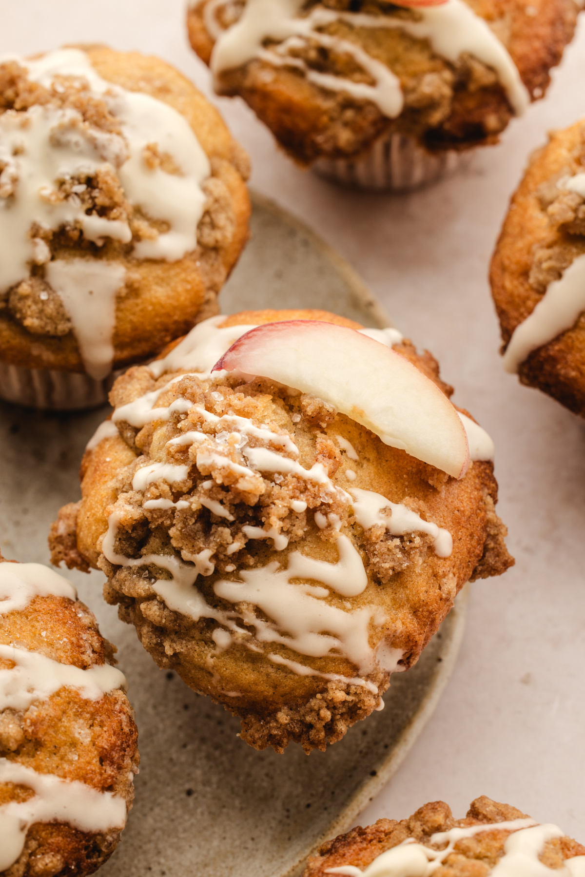 Peach coffee cake muffin topped with cinnamon streusel, vanilla glaze, and a fresh peach slice