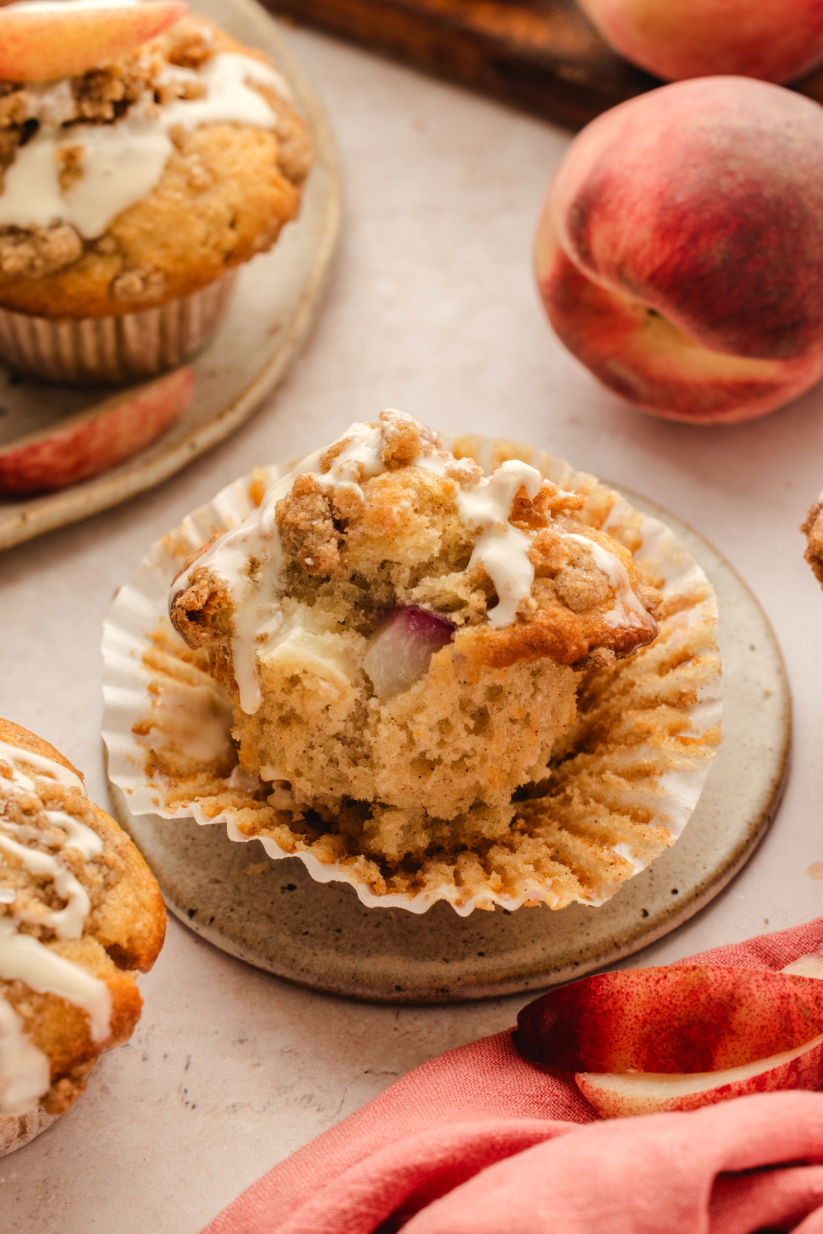 Peach coffee cake muffin with fresh peach pieces, cinnamon streusel, and vanilla glaze