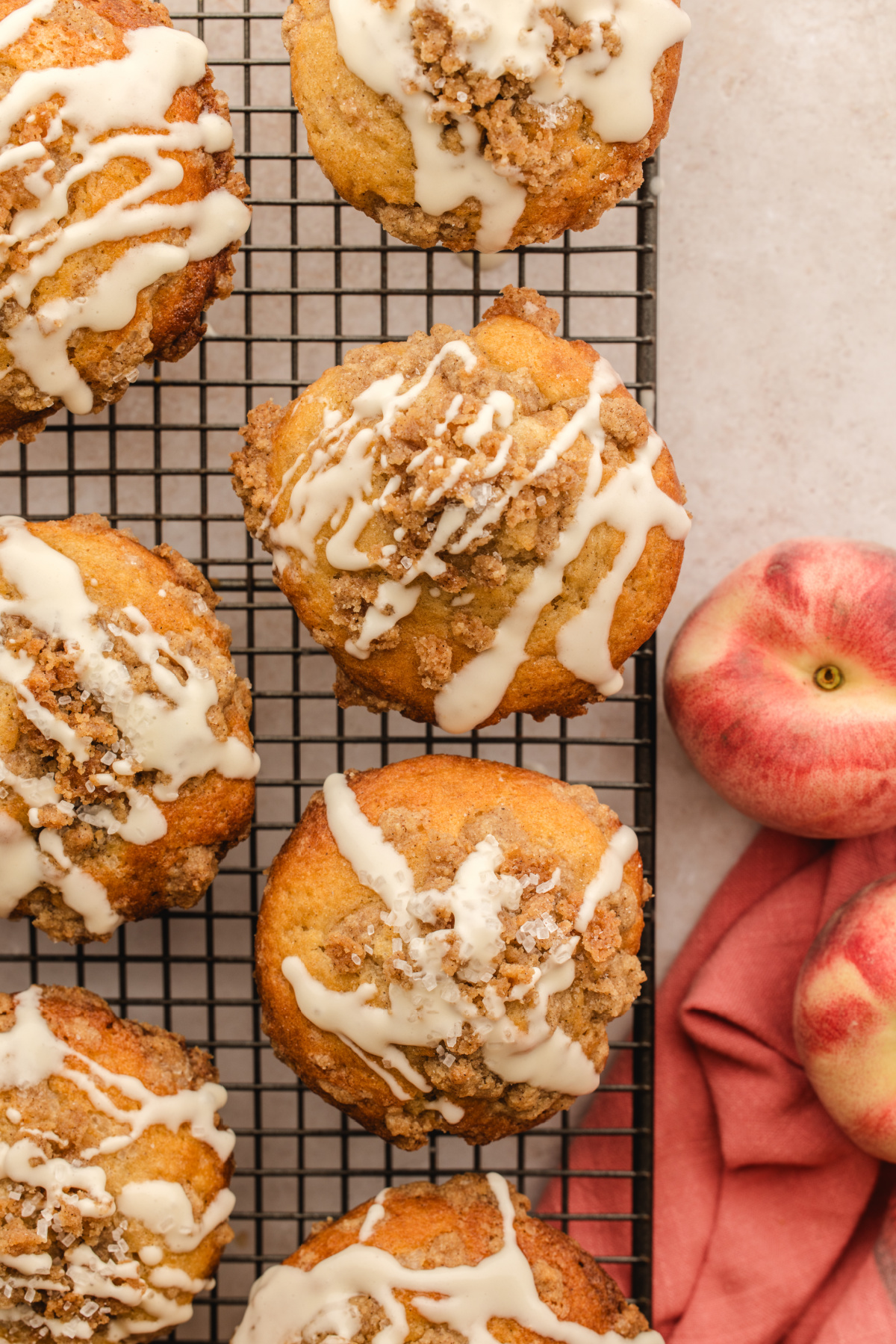 Peach coffee cake muffins with cinnamon streusel, vanilla glaze, and fresh peaches