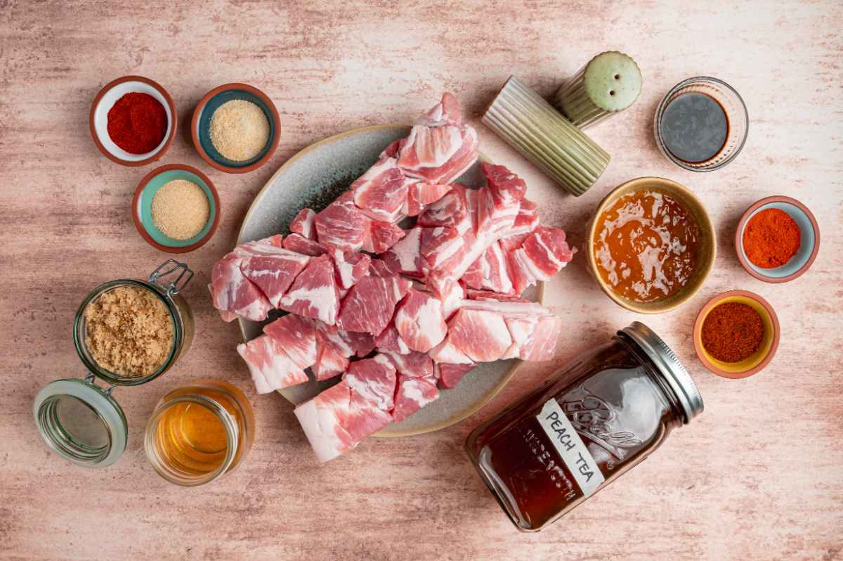 Ingredients for Peach Tea Pork Belly Burnt Ends including cubed skinless pork belly, peach tea, peach preserves, barbecue sauce, brown sugar, spices, and seasonings.