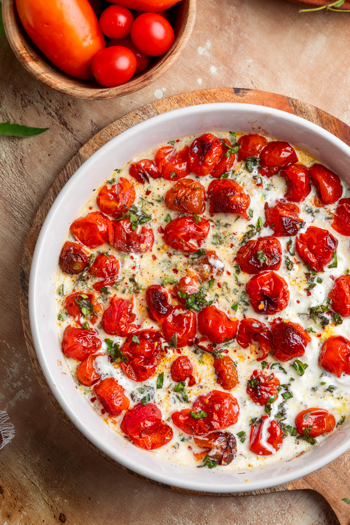 Overhead view of the finished roasted tomato burrata dip. Overhead view of roasted grape tomatoes and creamy burrata baked together with fresh basil, thyme, garlic, and lemon.