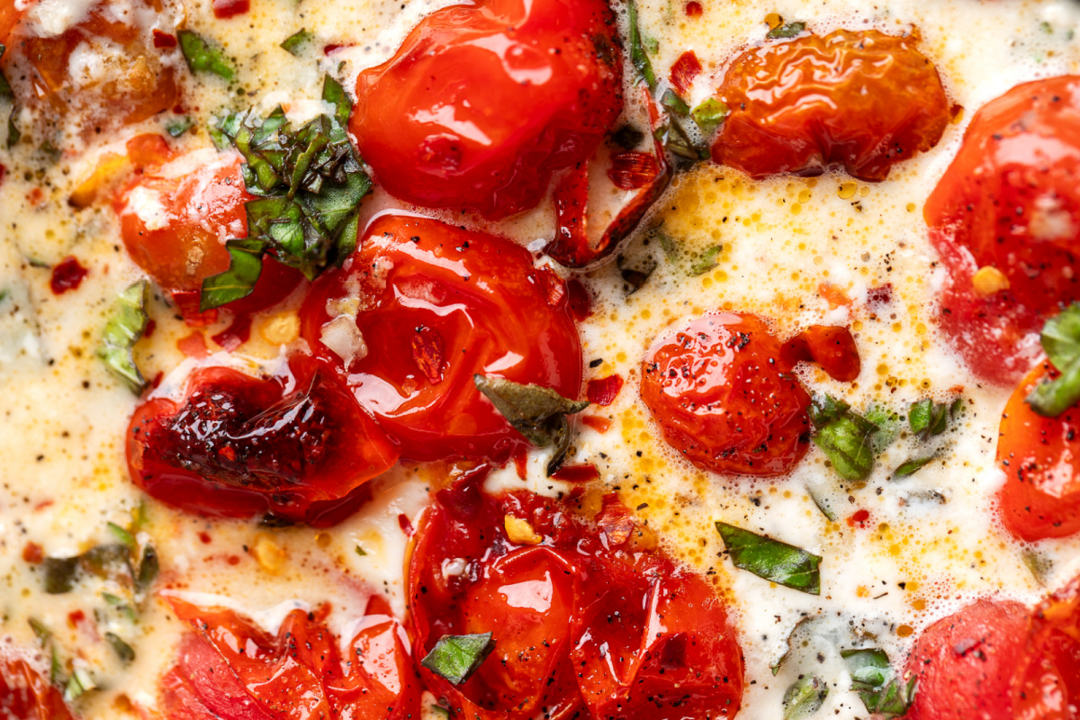 Close-up showing the creamy texture of the finished dip. Close-up of roasted grape tomatoes, creamy burrata, fresh basil, garlic, and herbs in the finished dip.