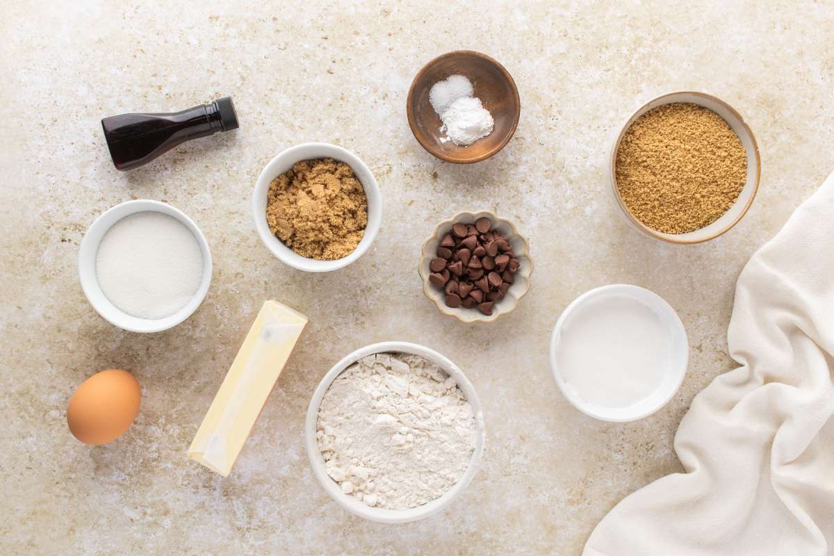 Ingredients for s'mores cookie bars including graham cracker crumbs, marshmallow creme, flour, butter, sugars, chocolate chips, vanilla, egg, baking powder, and salt.