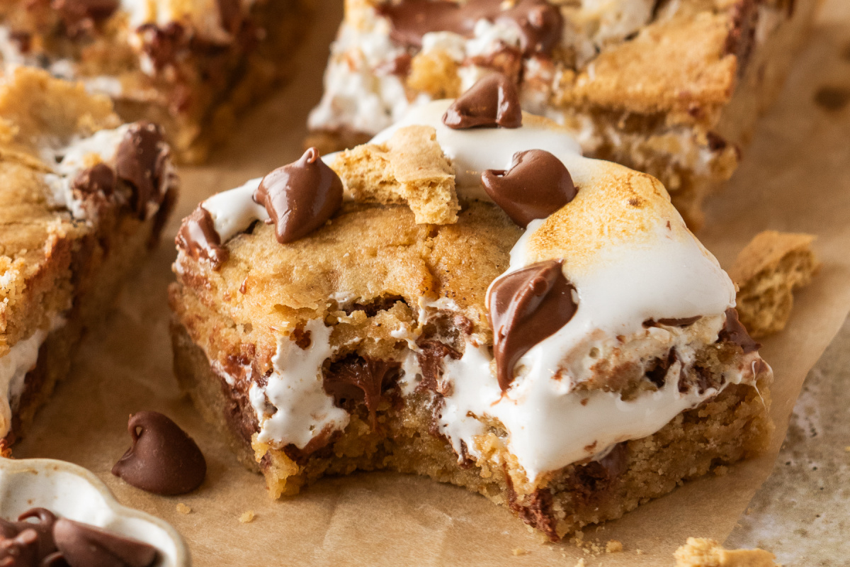 S'mores cookie bars with graham cookie dough, gooey marshmallow creme filling, and milk chocolate chips.