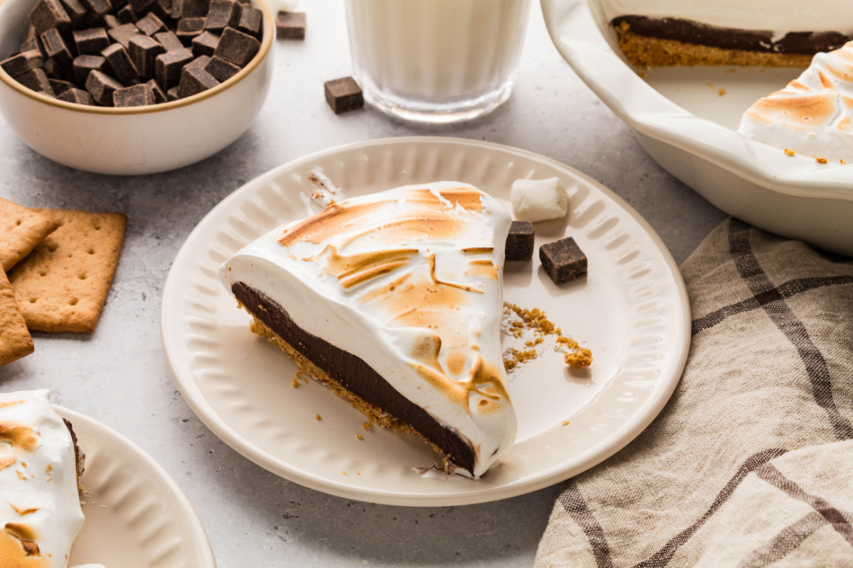 Slice of s'mores pie with chocolate ganache, homemade toasted marshmallow topping, and graham cracker crust.