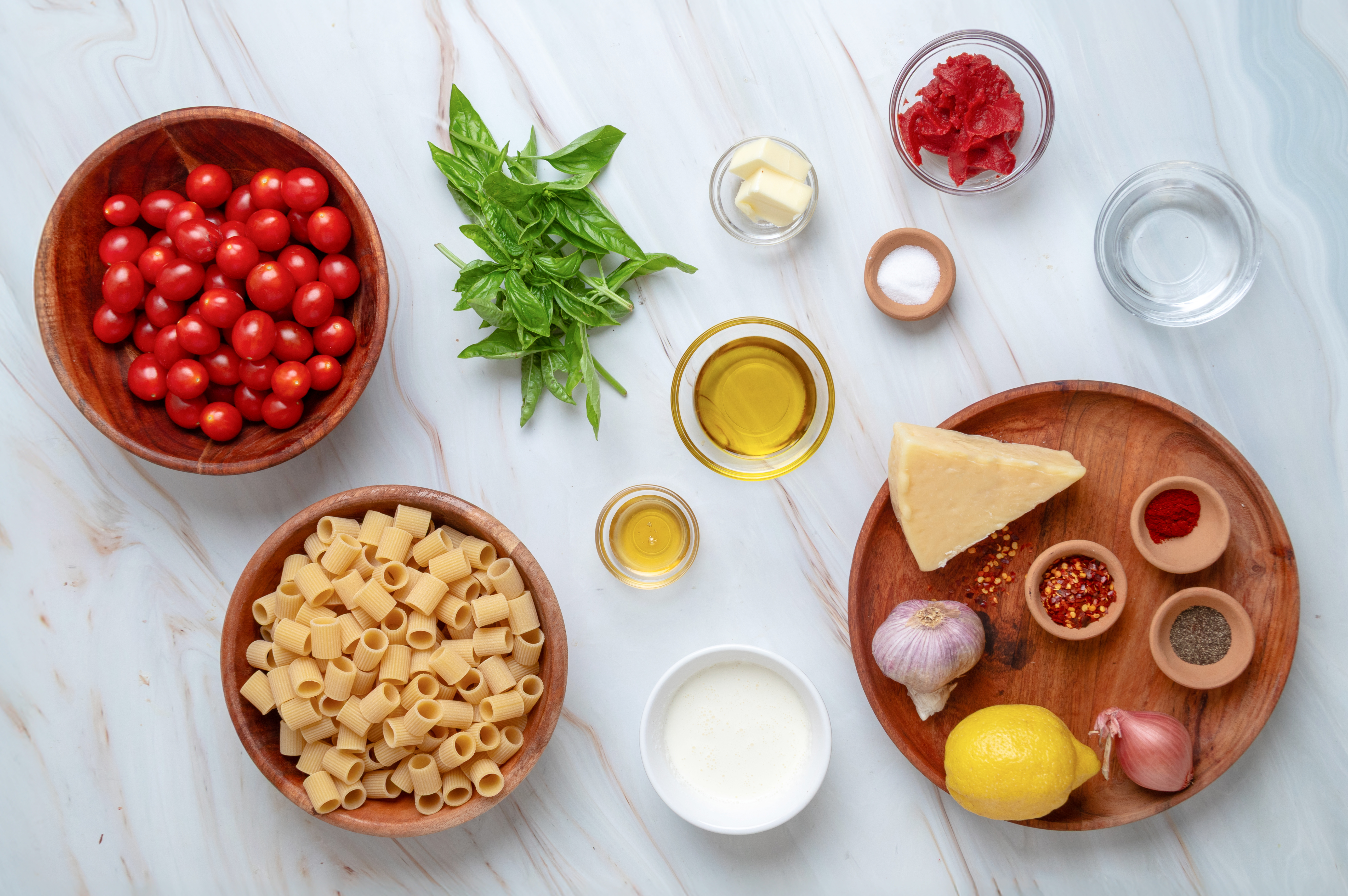 Everything you need to make spicy roasted tomato vodka pasta. Ingredients for spicy roasted tomato vodka pasta, including mezzi rigatoni, grape tomatoes, tomato paste, Parmesan, heavy cream, shallot, garlic, basil, vodka, butter, olive oil, lemon, and seasonings.