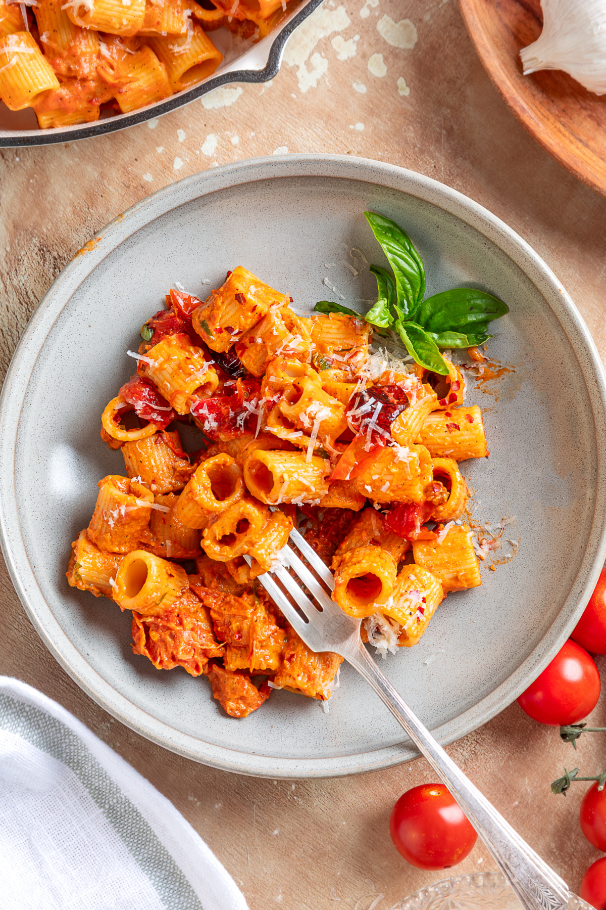 Spicy roasted tomato vodka pasta served with roasted grape tomatoes, basil, and Parmesan. A plated serving of spicy roasted tomato vodka pasta with roasted grape tomatoes, fresh basil, and grated Parmesan cheese.