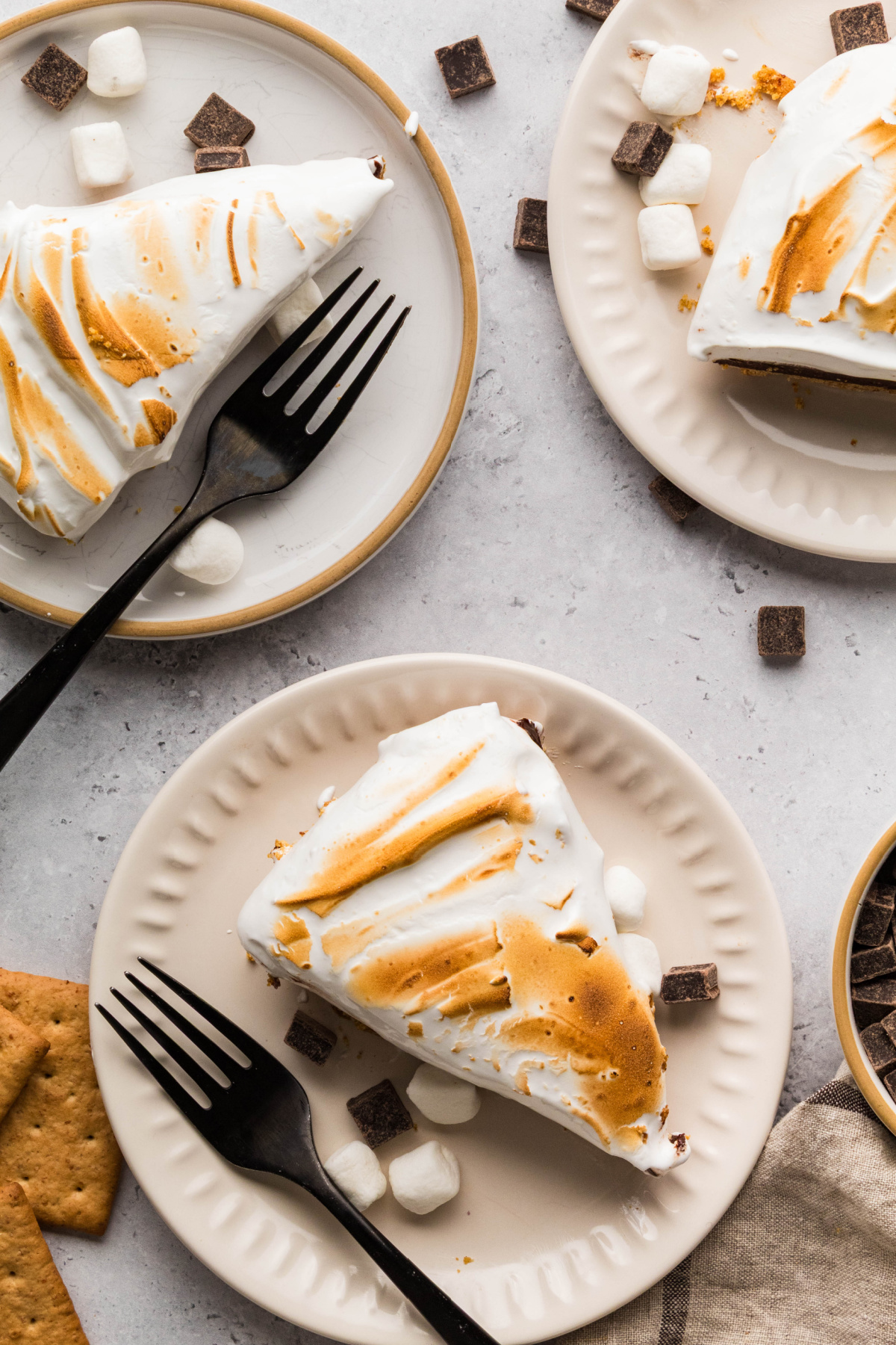 Three slices of chocolate pie with toasted homemade marshmallow topping and graham cracker crust.