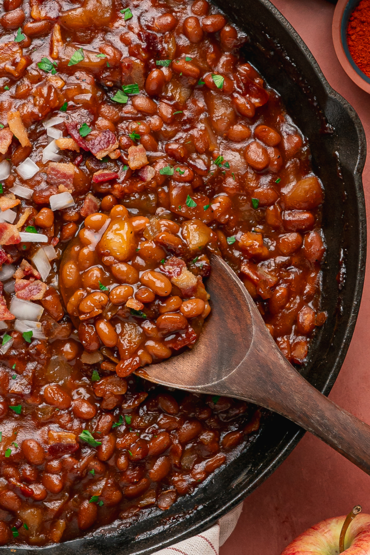 Apple pie baked beans with bacon and apples in a cast-iron skillet