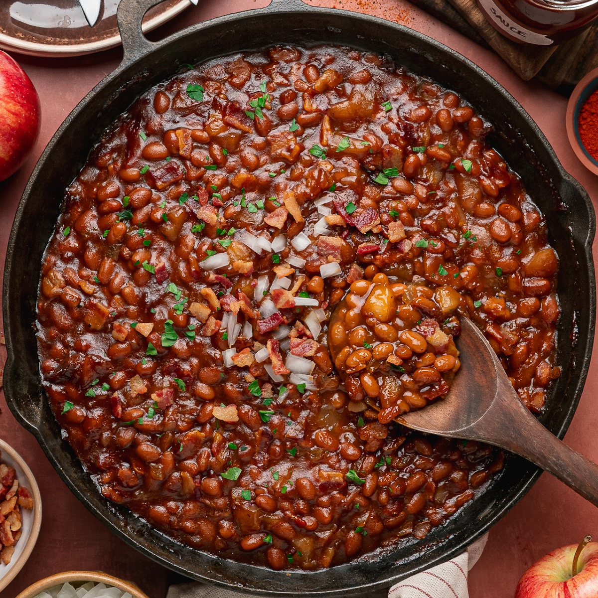 Apple pie baked beans with bacon and apple pieces in a cast-iron skillet