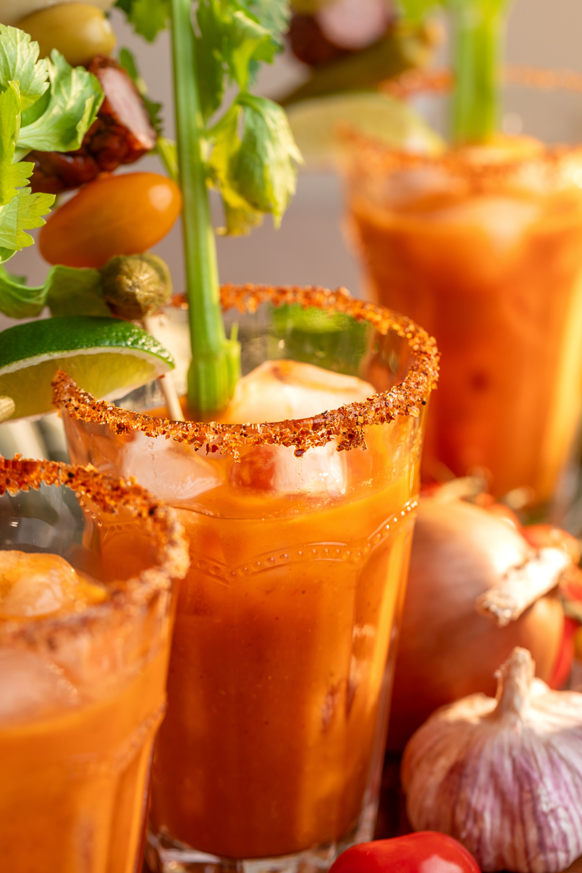 Smoky Bloody Mary cocktails served over ice with Tajín rims and loaded garnishes Bloody Mary cocktails made with smoked tomato mix over ice with Tajín rims, celery, lime and savory garnishes