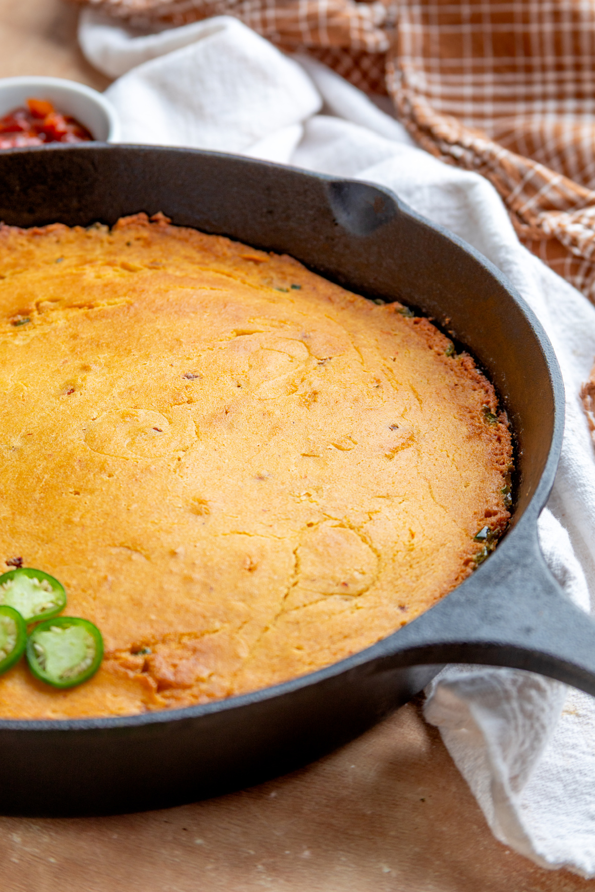 Freshly baked skillet cornbread flavored with chipotle, adobo and jalapeños Chipotle cornbread baked in a cast-iron skillet with fresh jalapeños visible around the cornbread