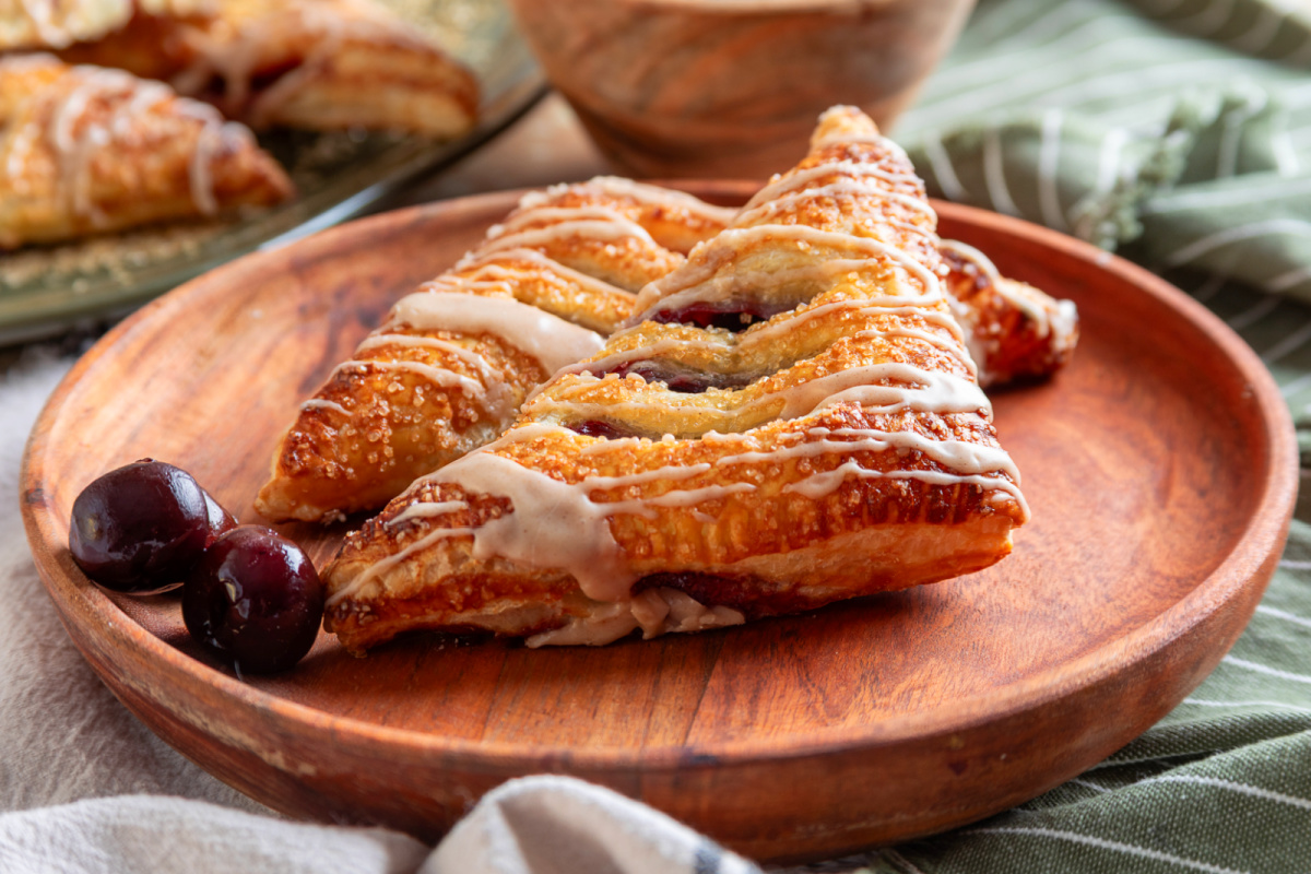 Golden puff pastry turnovers with dark cherry filling and bourbon glaze Cherry turnovers topped with cinnamon bourbon glaze and coarse sugar