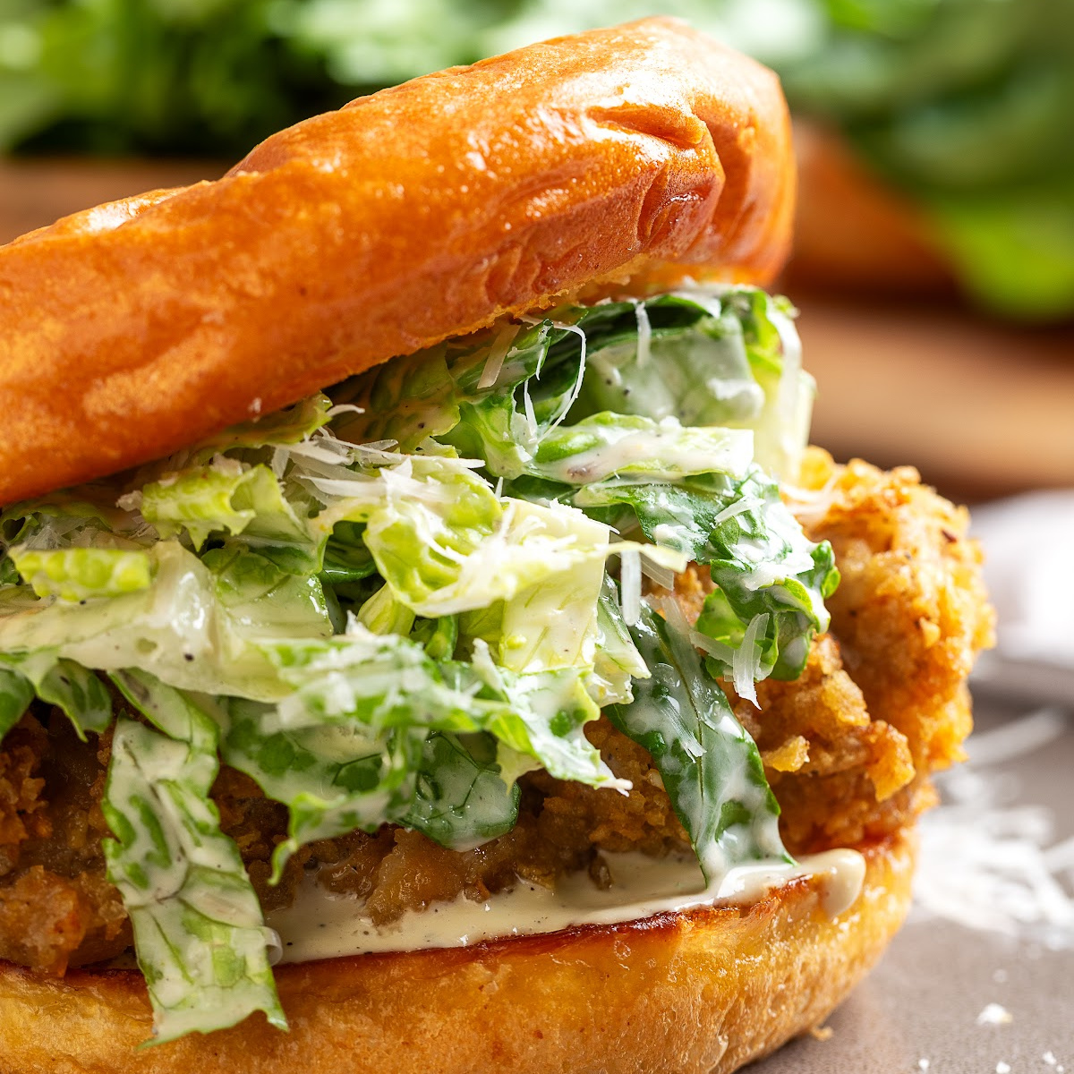 Chicken Caesar salad sandwich with crispy potato chip-crusted chicken, homemade Caesar salad, Parmesan cheese, and a toasted brioche bun.