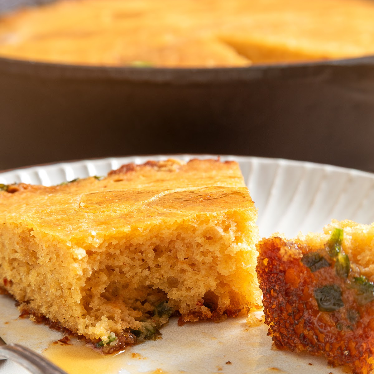 Chipotle hot honey skillet cornbread slice showing the tender interior, jalapeños and browned bottom