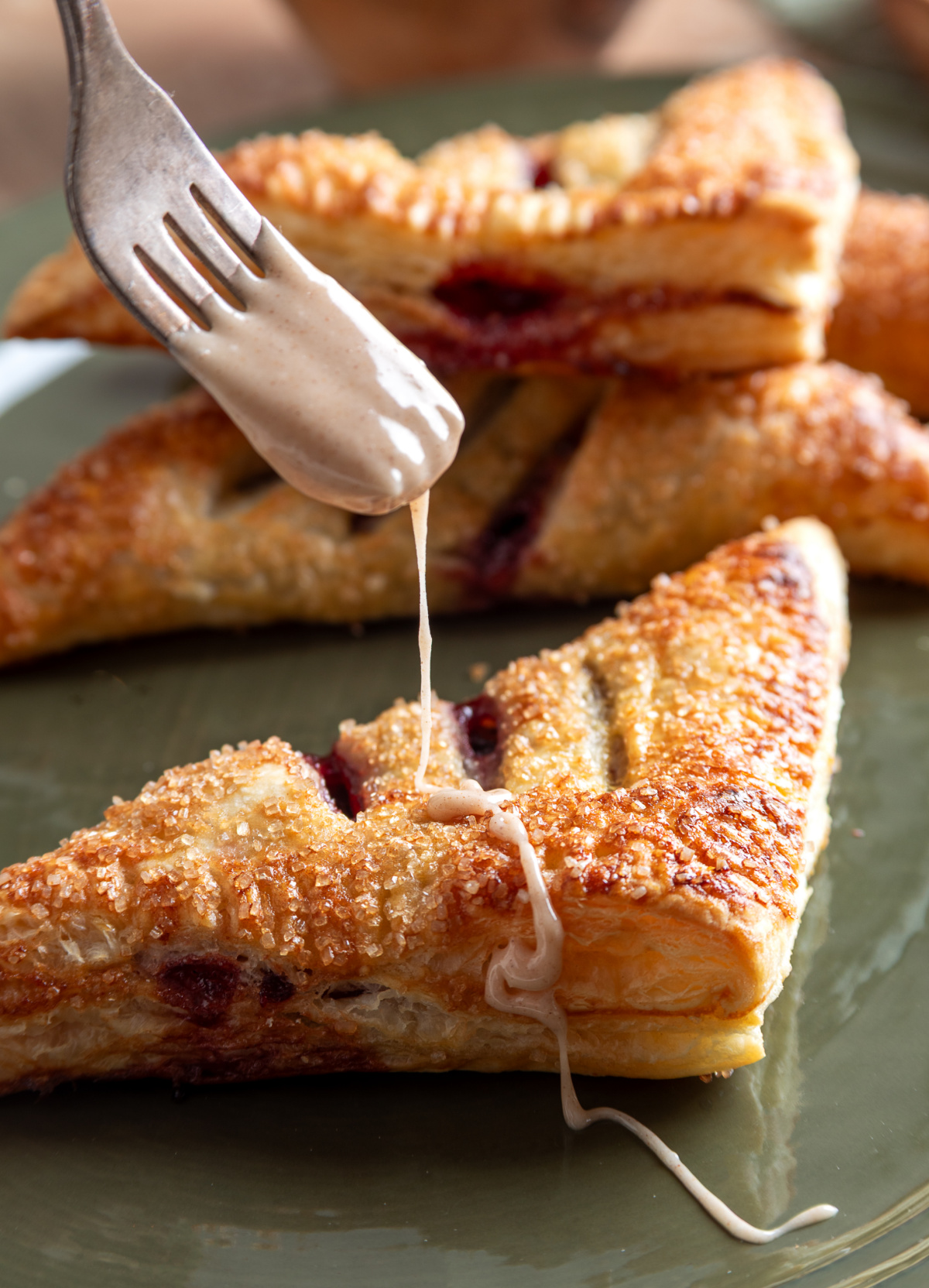Drizzling cinnamon bourbon glaze over a freshly baked cherry pastry cinnamon-bourbon-glaze-puff-pastry-turnover