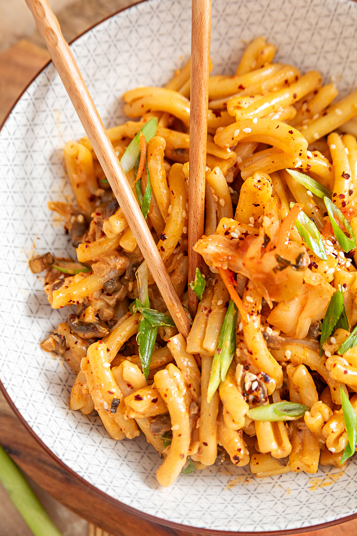 Casarecce with creamy gochujang mushroom sauce, kimchi, gochugaru and green onions Close-up of creamy gochujang pasta with diced mushrooms, kimchi, green onions and sesame seeds