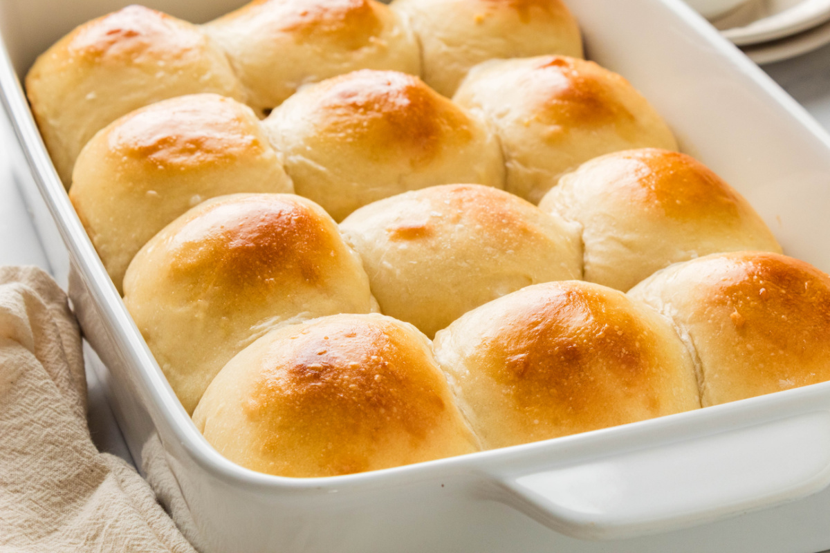 Homemade milk bread rolls with soft pull-apart sides and golden brown tops in a baking dish.