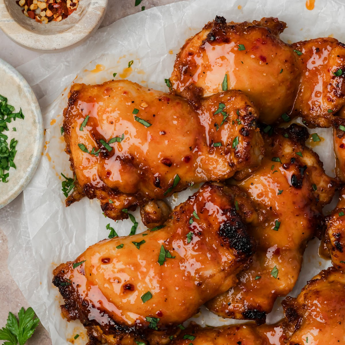 Brushing homemade hot honey glaze onto roasted chicken thighs before broiling.