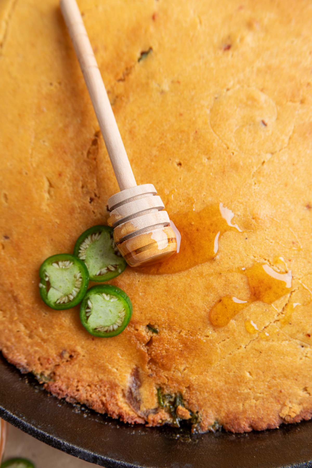 Hot honey drizzled over smoky chipotle and jalapeño cornbread baked in cast iron Chipotle hot honey skillet cornbread drizzled with hot honey and topped with fresh jalapeño slices