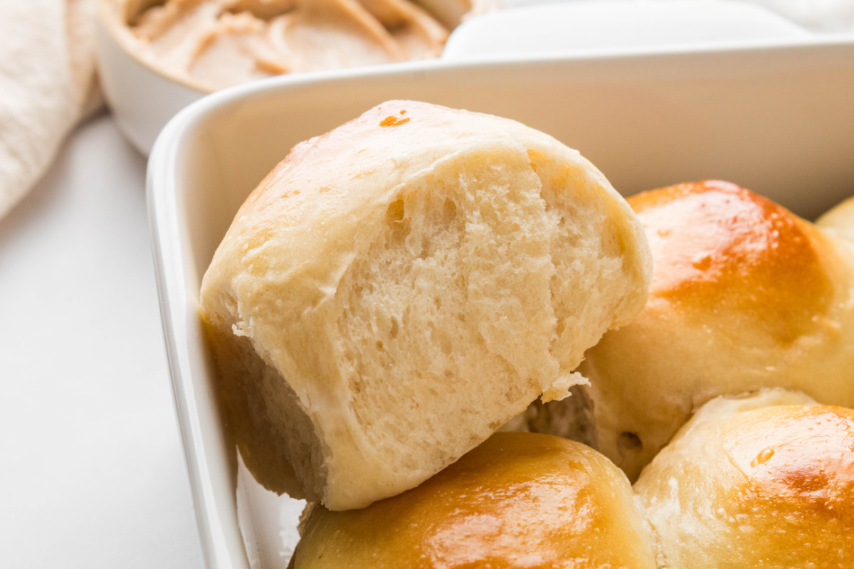 Soft milk bread roll pulled from the baking dish to show the tender interior.