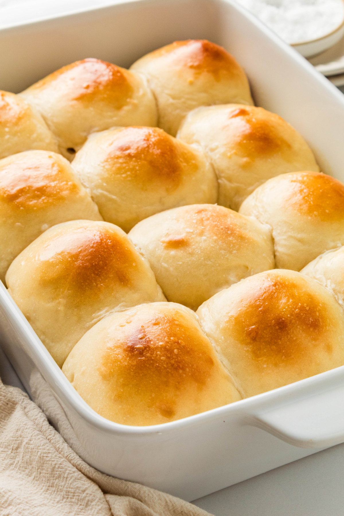 Soft milk bread rolls baked together in a white baking dish with golden brown tops.