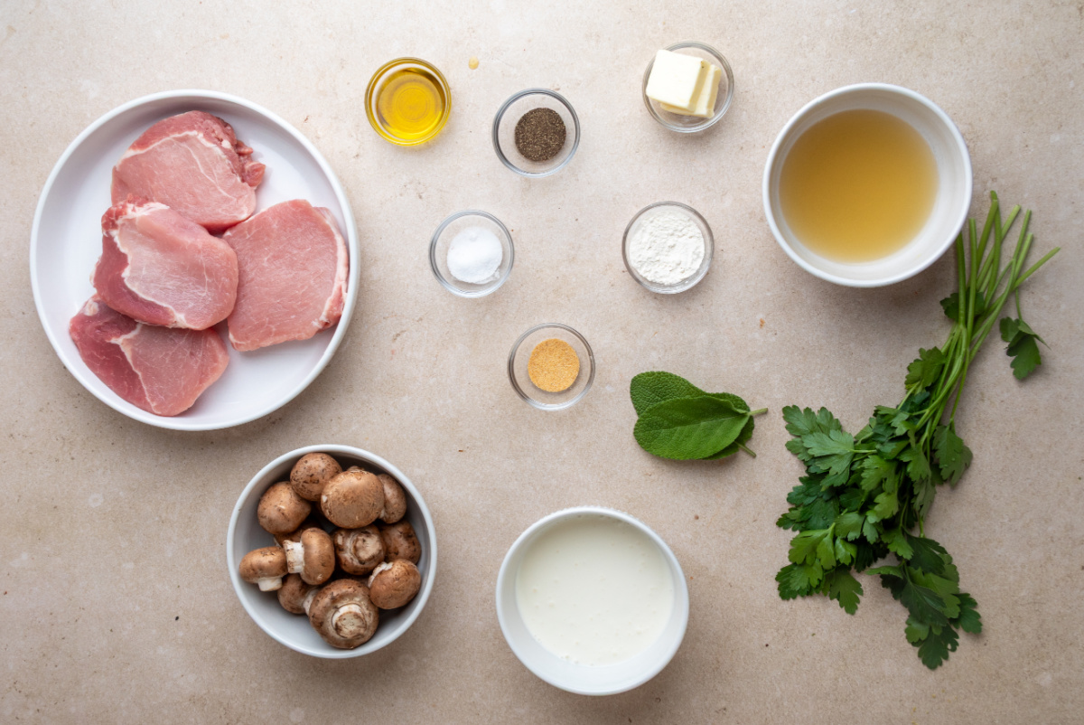 Boneless pork chops, mushrooms, fresh sage, cream, broth and seasonings ready for the recipe. Ingredients for creamy mushroom pork chops including boneless pork chops, baby portobello mushrooms, cream and fresh sage