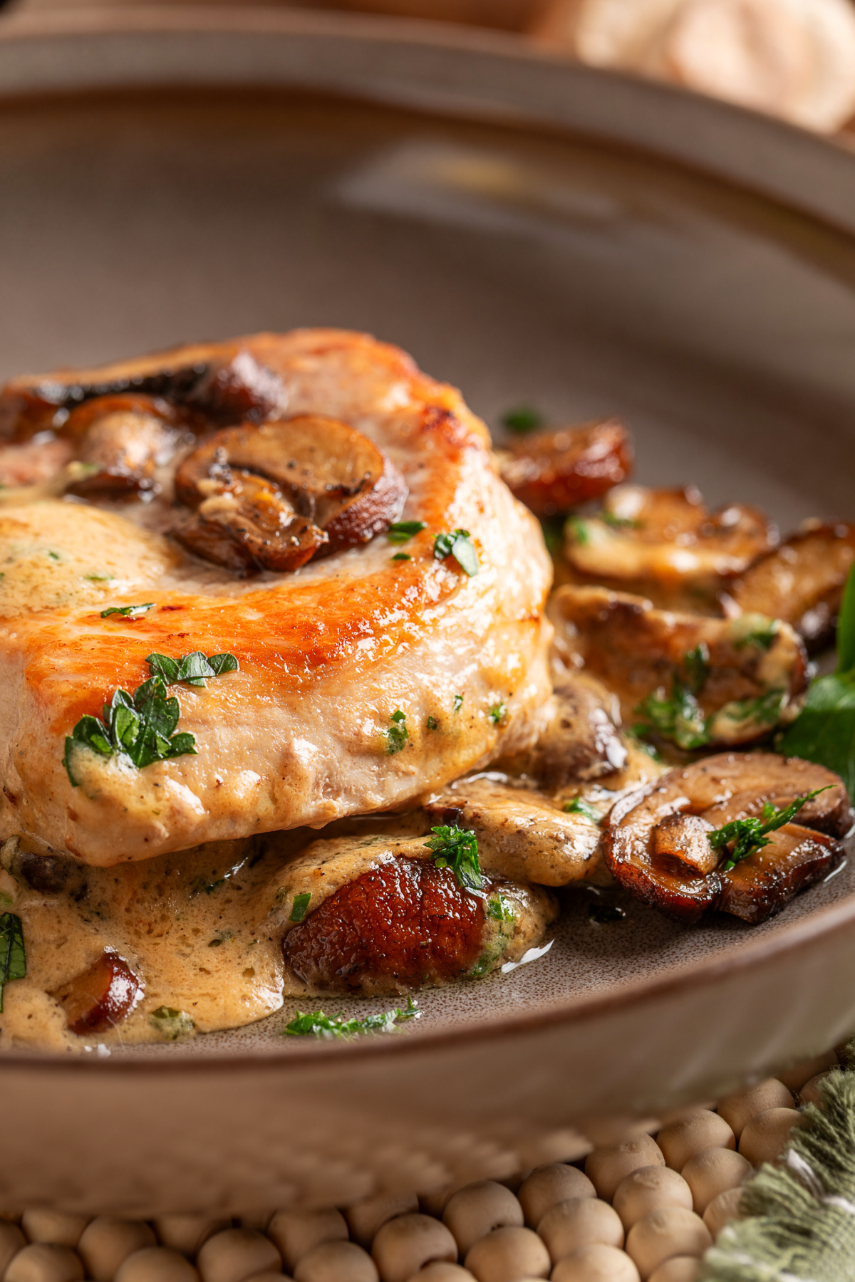 Thick seared pork chop served over sage cream sauce with deeply browned roasted mushrooms. Seared boneless pork chop with roasted mushrooms, fresh parsley and sage cream sauce