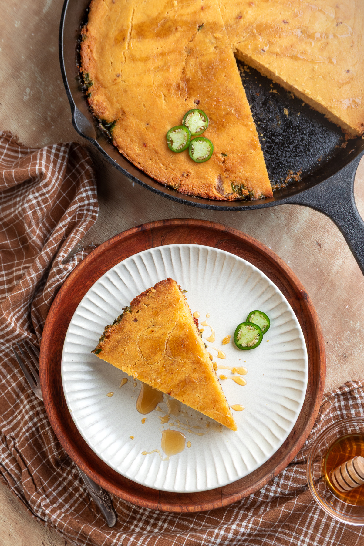 Hot honey and jalapeño cornbread served alongside the freshly baked skillet Slice of chipotle jalapeño cornbread served with hot honey beside the cast-iron skillet