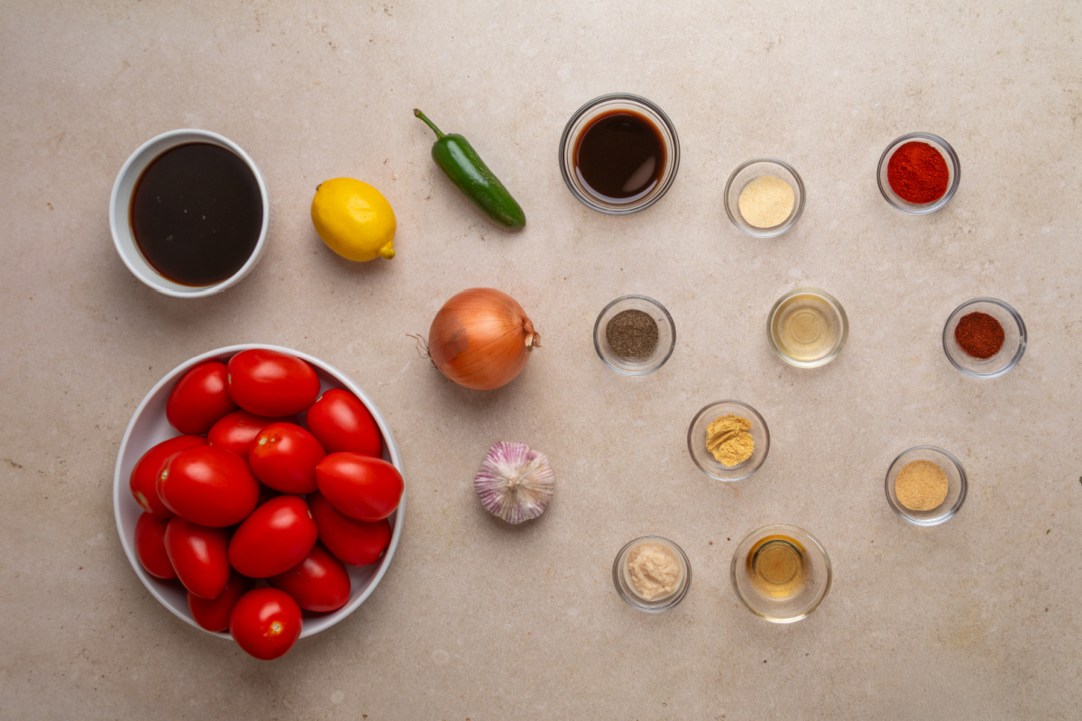 Roma tomatoes, aromatics, beef consommé, horseradish, Worcestershire and seasonings for homemade Bloody Mary mix Ingredients for smoked tomato Bloody Mary mix including Roma tomatoes, onion, garlic, jalapeño, lemon, Worcestershire and spices