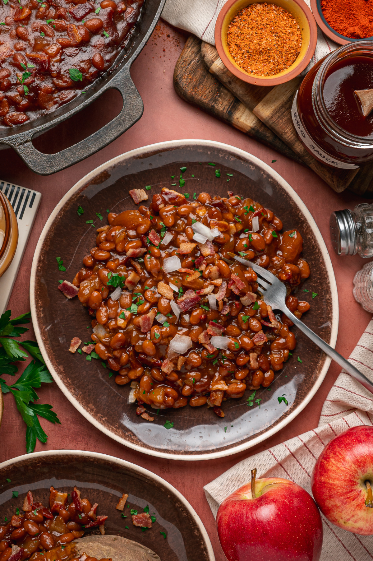 Smoky baked beans with apple pieces, bacon and onion served on a platter