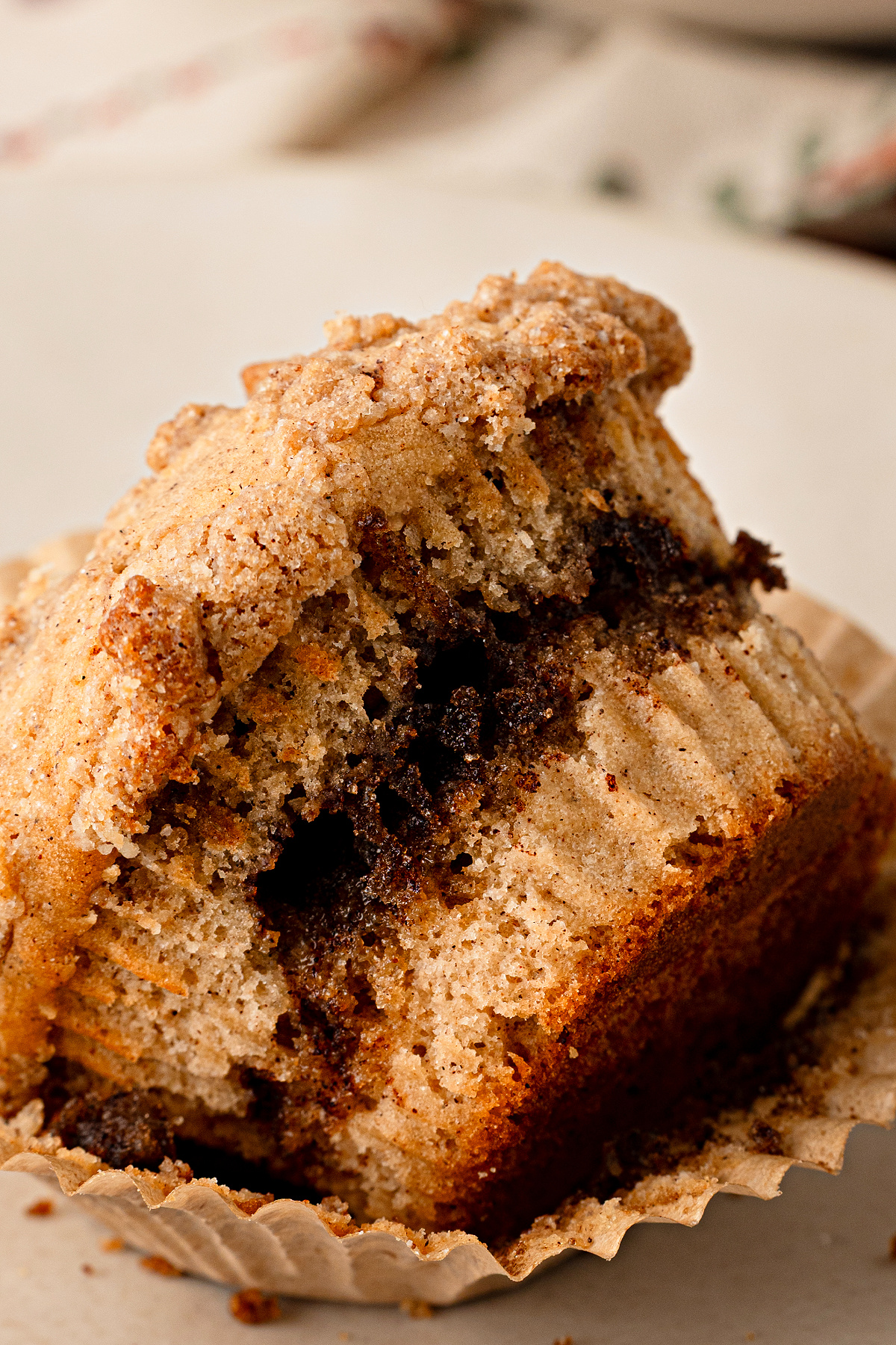 Apple cider streusel muffin with a brown sugar cinnamon ribbon, cider-doughnut spices and buttery streusel. Apple cider streusel muffin broken open to show the brown sugar cinnamon ribbon and cinnamon streusel topping.