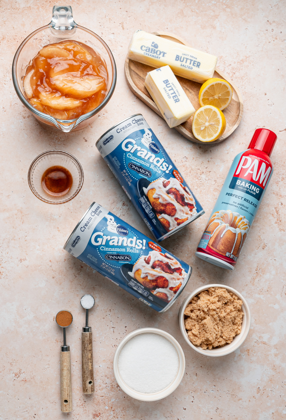 Ingredients for apple pie cinnamon roll monkey bread including refrigerated cinnamon rolls, apple pie filling, butter, brown sugar, cinnamon and lemon.