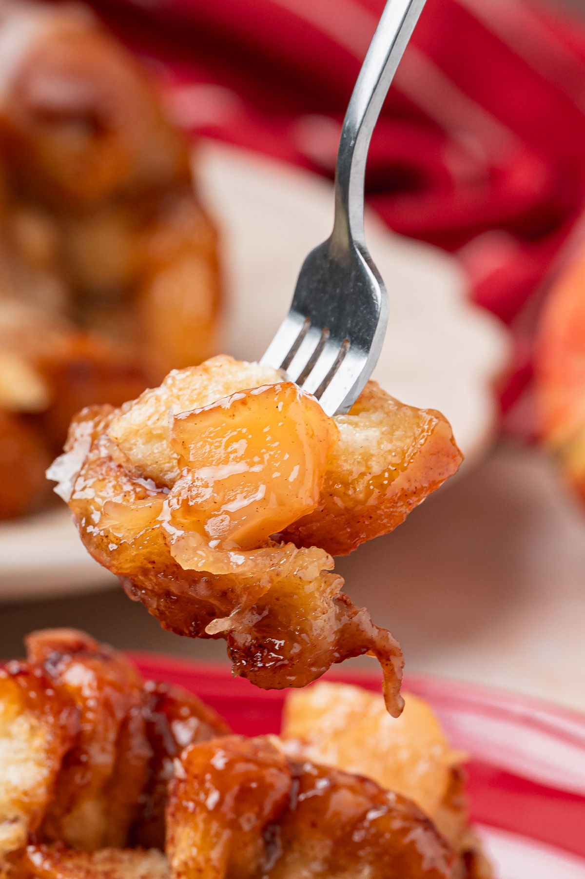 Forkful of cinnamon roll monkey bread with soft apple pie filling and caramelized brown sugar sauce.