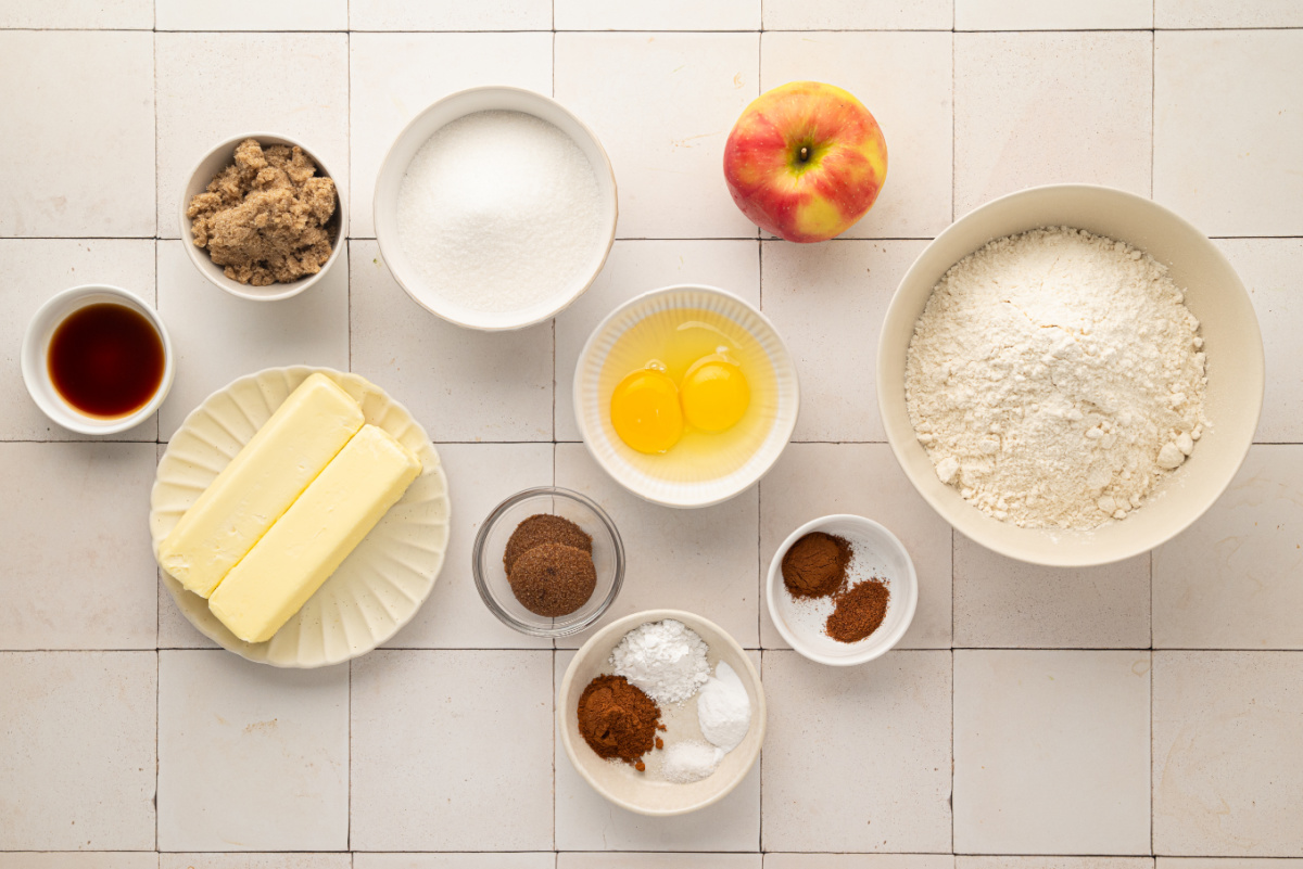 Ingredients for apple snickerdoodles including fresh apple, flour, butter, sugars, eggs and cinnamon