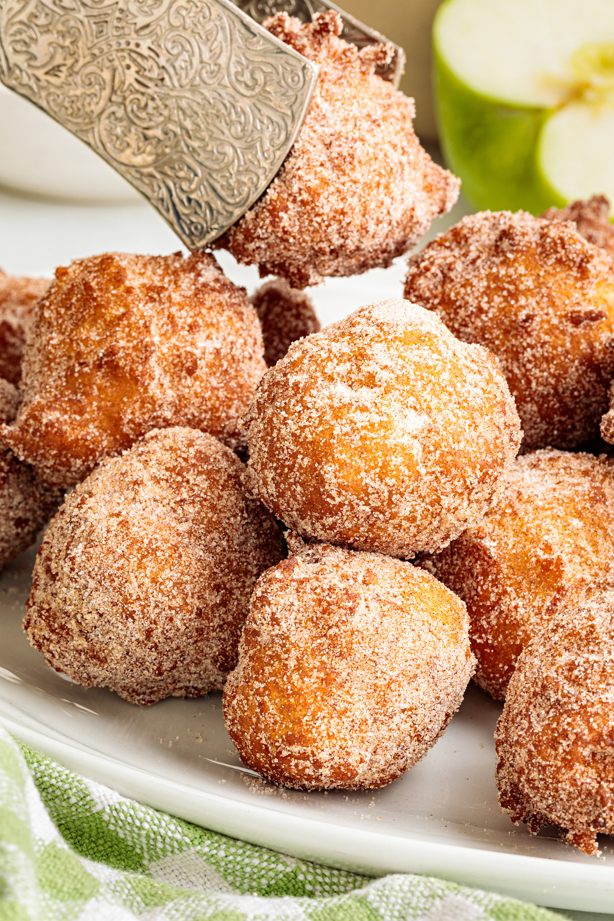 Warm cinnamon sugar applesauce fritters ready for serving Applesauce fritters rolled in cinnamon sugar with a Granny Smith apple in the background
