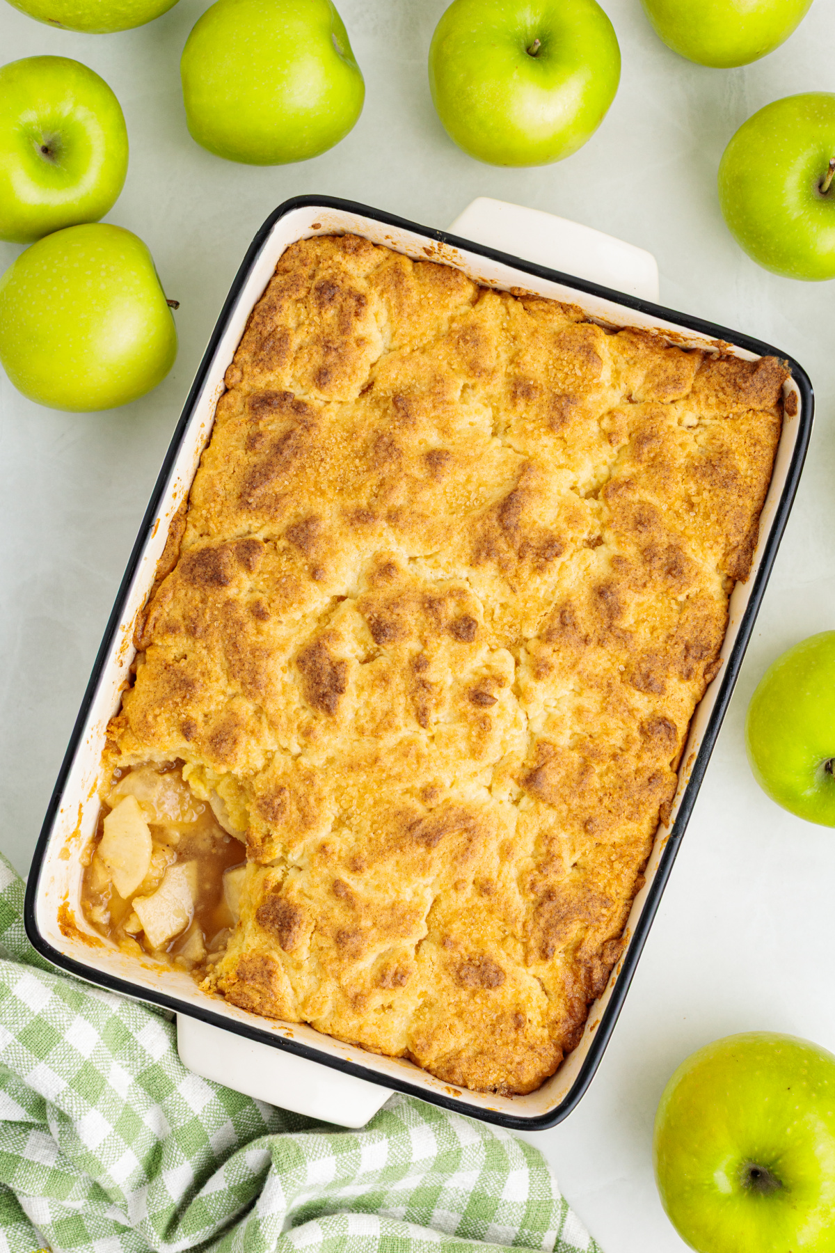 Golden butter cake topping baked over a thick layer of cinnamon-spiced Granny Smith apples. Baked apple cobbler with a golden butter cake topping and cinnamon-spiced Granny Smith apple filling.
