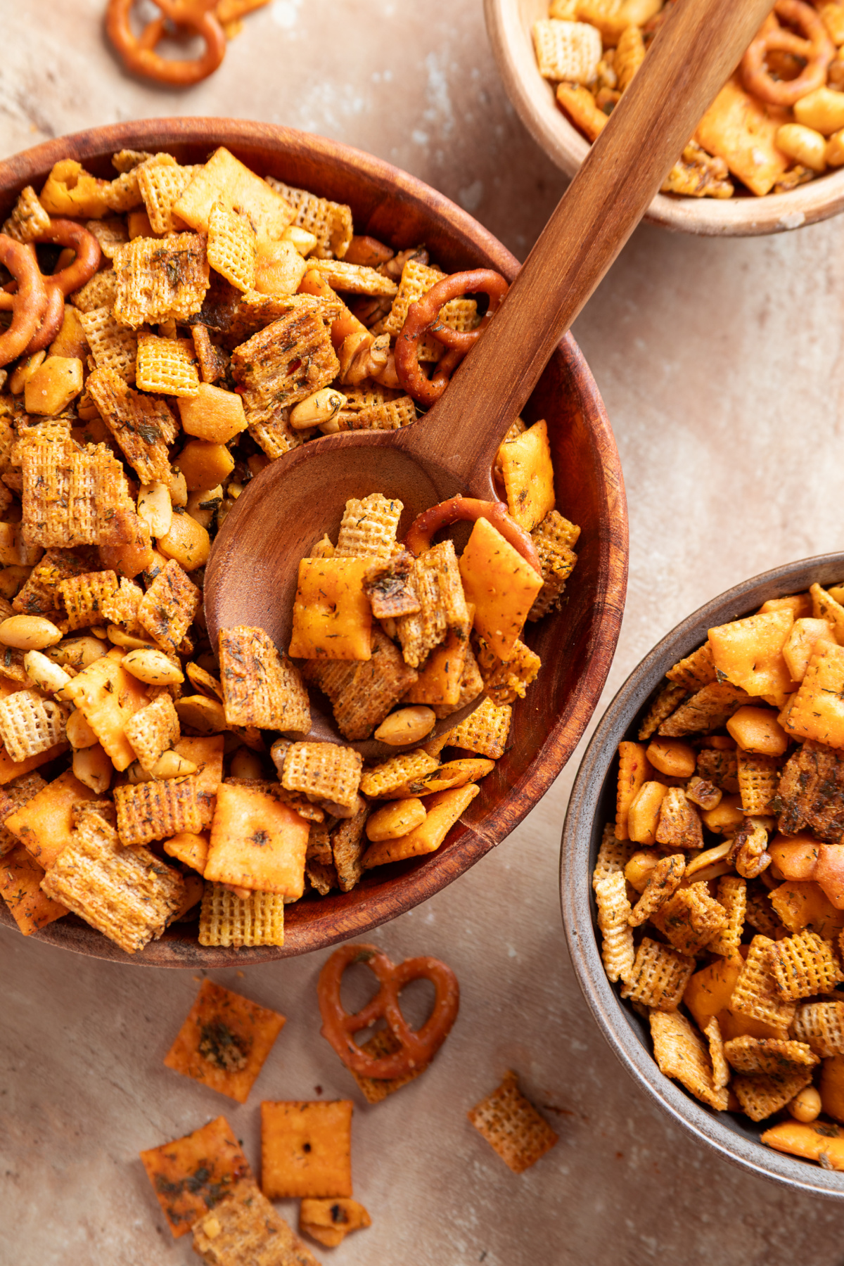 Baked Chex mix with Cheez-It crackers, Triscuits, pretzels, peanuts and walnuts served in wooden bowls