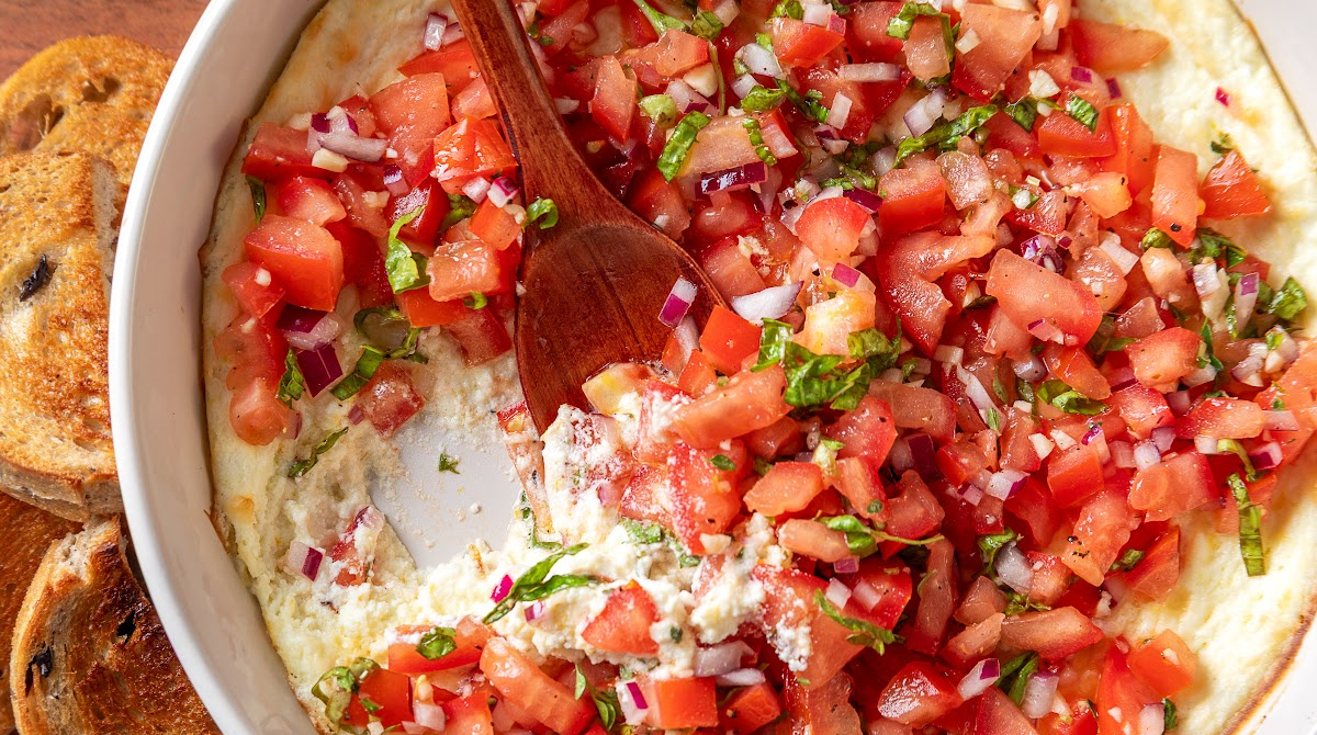 Creamy Baked Feta Bruschetta Dip with Fresh Tomatoes Creamy baked feta topped with fresh Roma tomato bruschetta, basil, red onion and thyme, with toasted bread alongside.