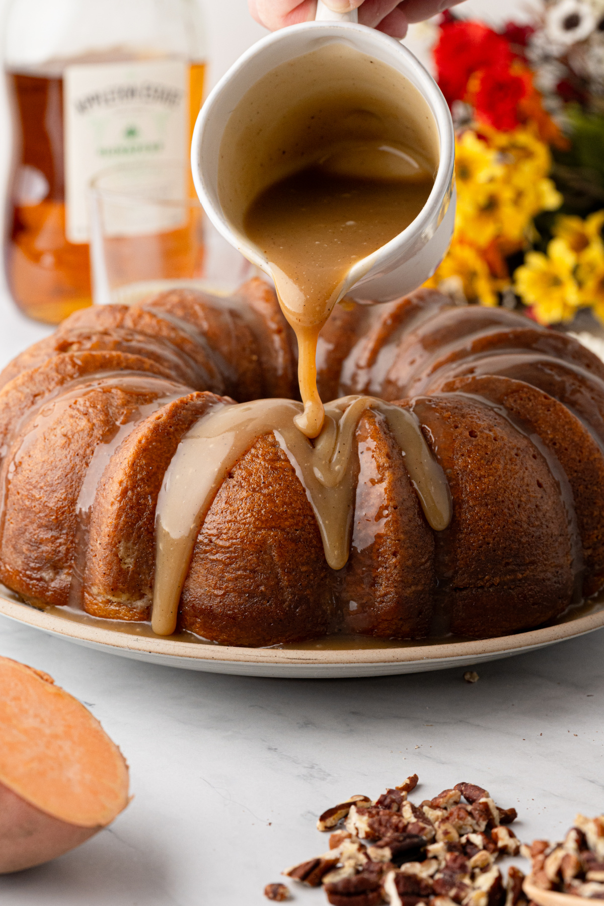 Thick dark rum caramel poured over the cooled brown butter sweet potato Bundt cake before the toasted pecan finish. Buttered rum caramel being poured over sweet potato Bundt cake before adding the toasted pecans.