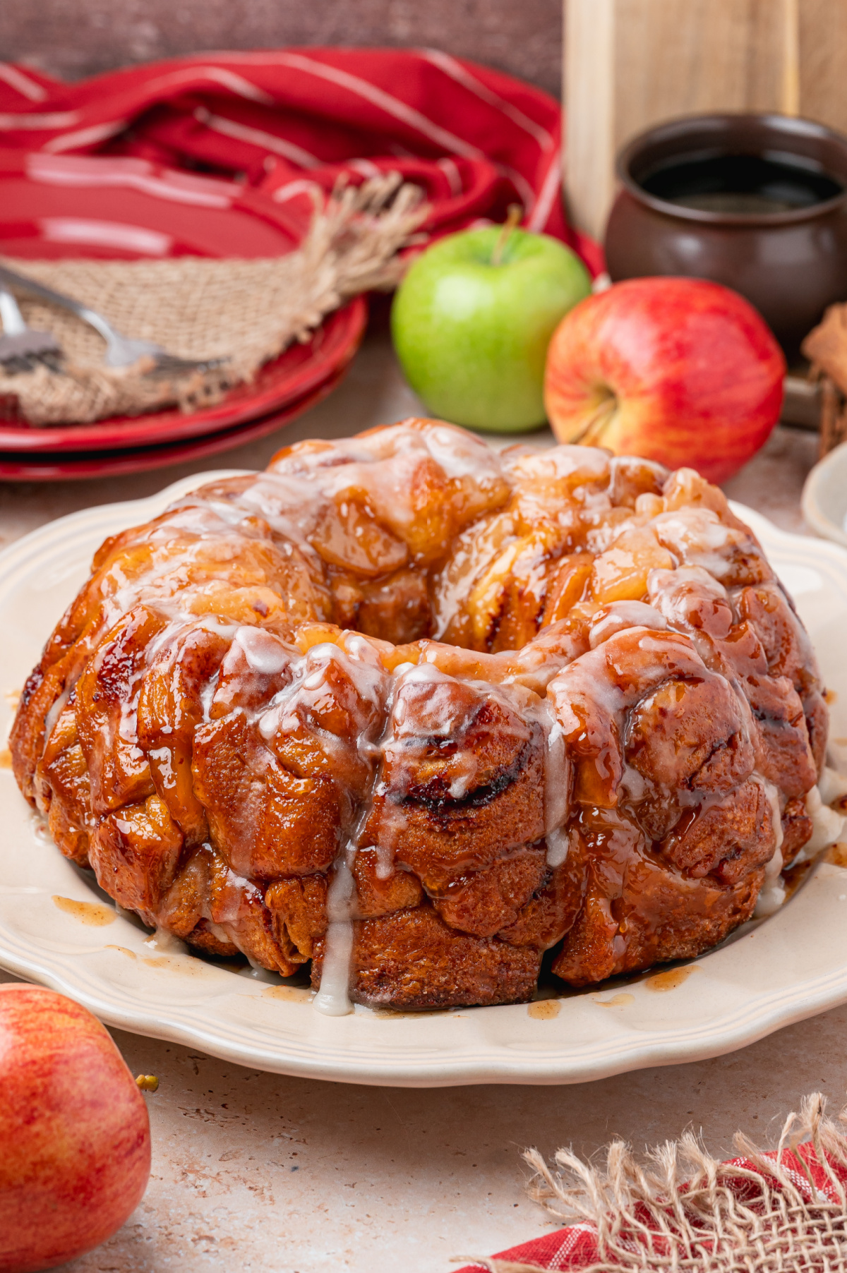 Caramelized cinnamon roll monkey bread with apple pie filling and warm icing on a serving platter.