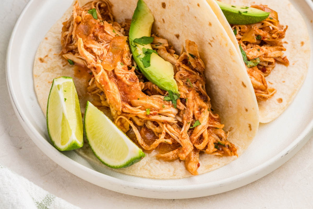 Slow cooker chipotle chicken tacos with sliced avocado, cilantro and lime