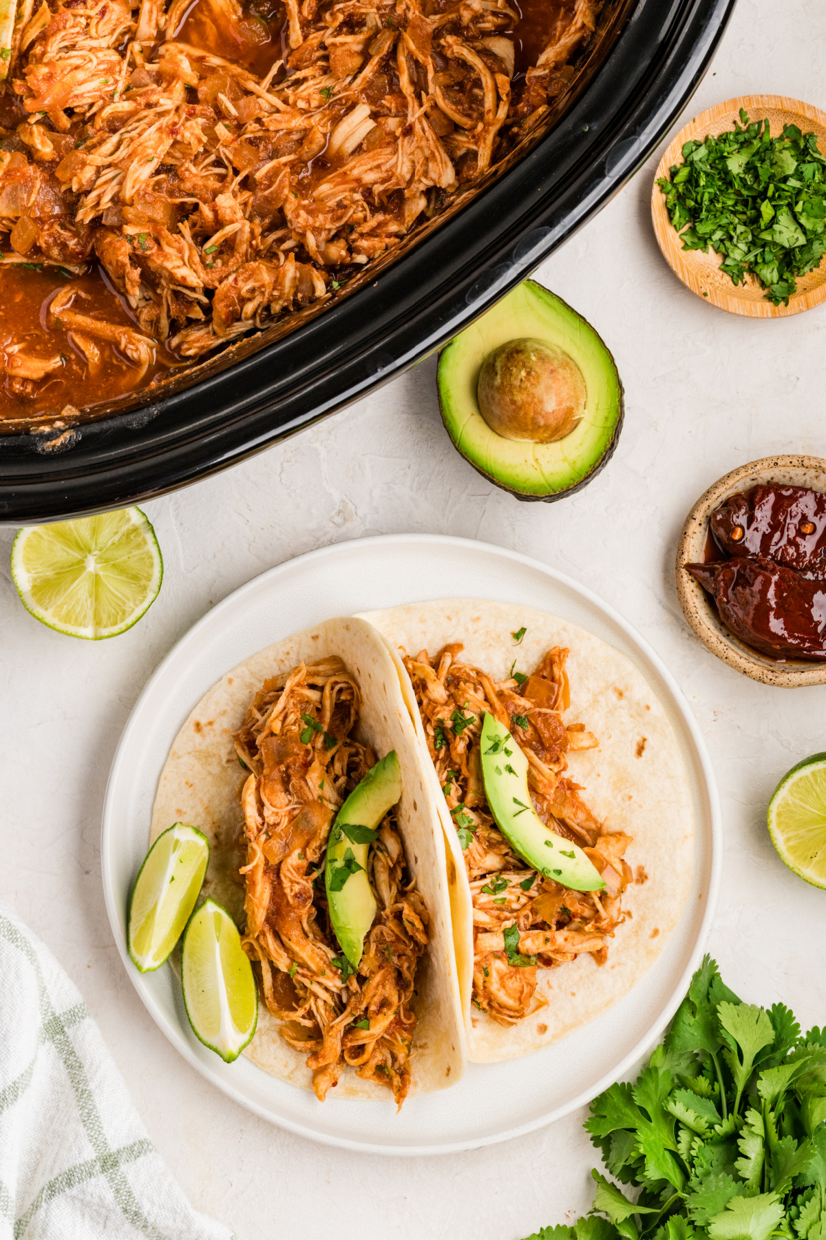 Chipotle chicken tacos with avocado and cilantro beside the slow cooker