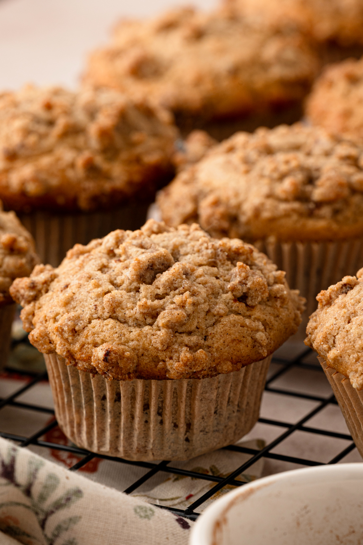 Cider-spiced muffins cooling on a wire rack with buttery cinnamon streusel topping. cider-spiced-muffins-cinnamon-streusel-topping