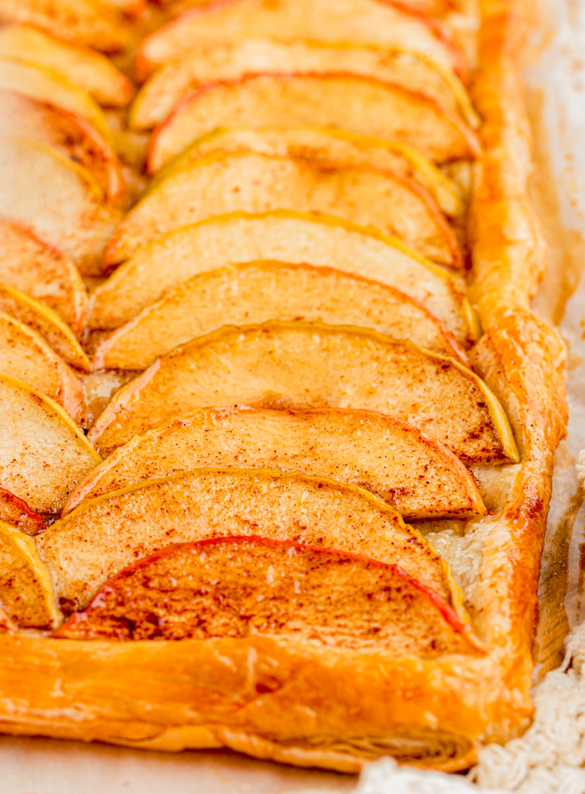 Thin Granny Smith and Dazzle apple slices baked over golden puff pastry Close-up of thin cinnamon apple slices baked on flaky golden puff pastry
