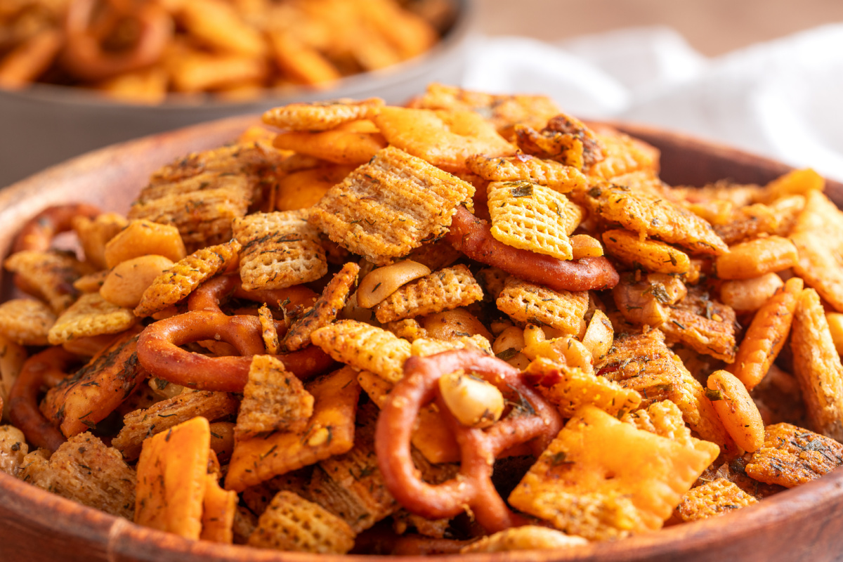 Cowboy butter Chex mix with pretzels, Cheez-It crackers, Triscuits, peanuts and walnuts coated in herbs and seasonings