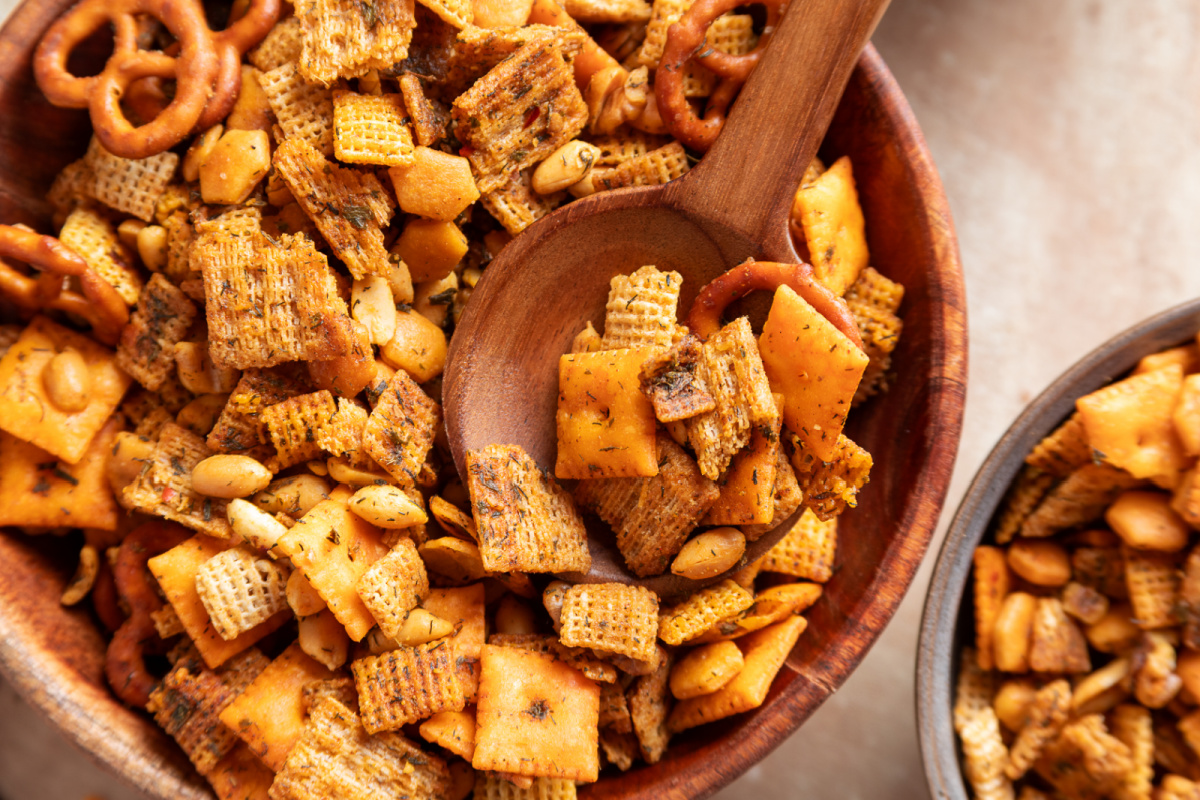 Cowboy butter snack mix with Chex cereal, Cheez-It crackers, Triscuits, pretzels, peanuts and walnuts in a wooden bowl