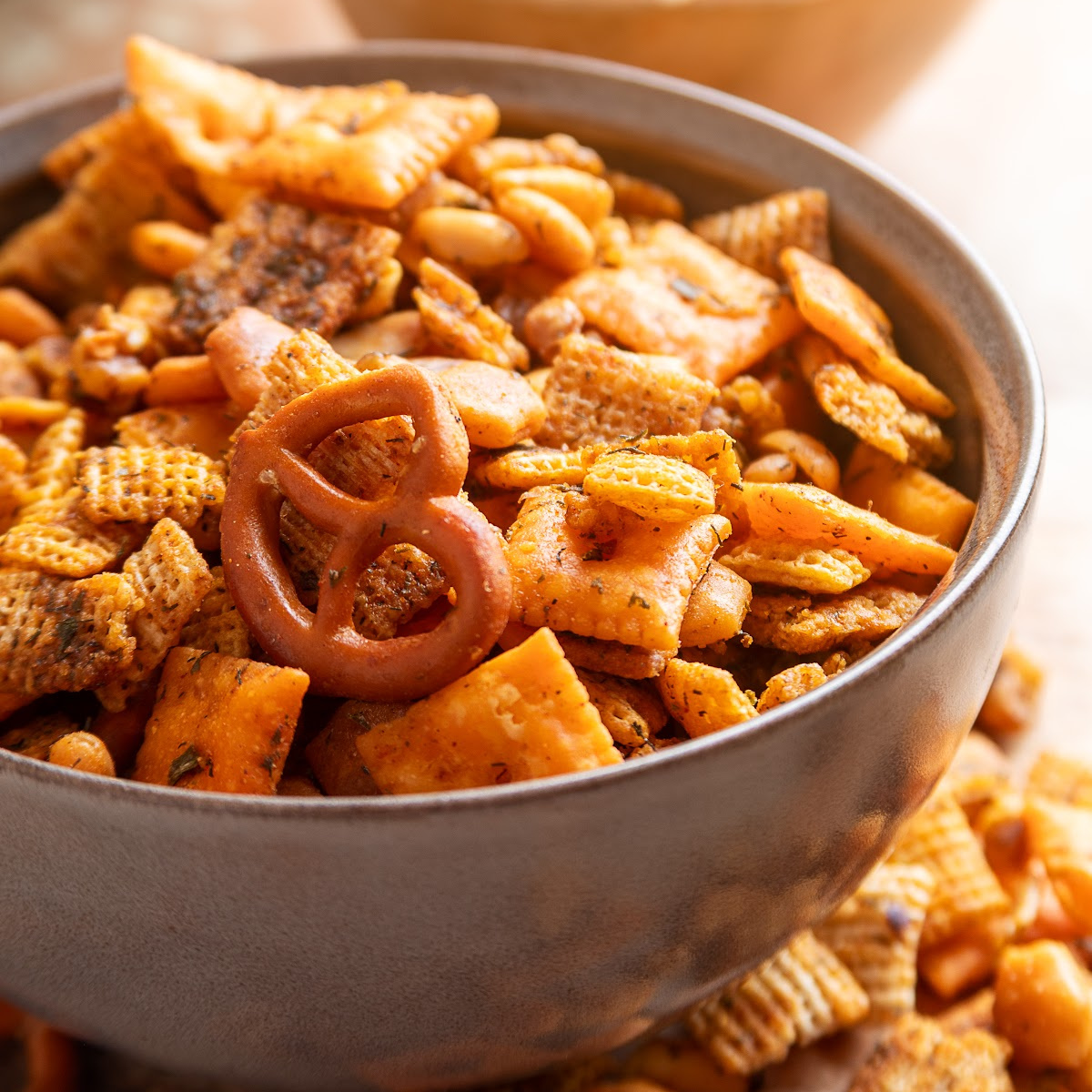 Bowl of cowboy butter snack mix with Chex cereal, Cheez-It crackers, Triscuits, pretzels, peanuts and walnuts.