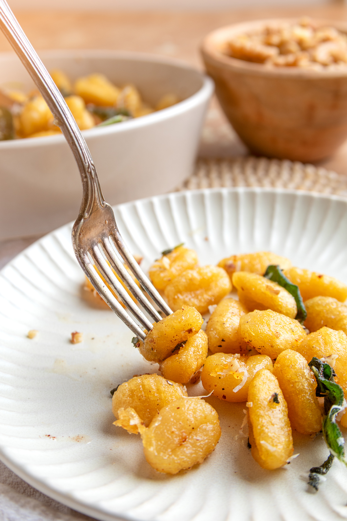 Pan-fried potato gnocchi with brown butter, toasted nuts and crisp sage. Crispy potato gnocchi with sage brown butter, Parmesan and fried sage leaves served on a plate.
